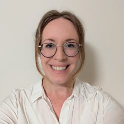 Brigid smiling wearing glasses and a white shirt