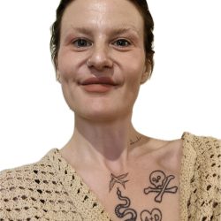 A photo of Hannah facing the camera and smiling. Hannah has short, dark hair and is wearing a beige crocheted top.